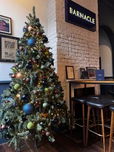 Christmas styling at The Barnacle restaurant, featuring a beautifully decorated Christmas tree with colourful baubles, oversized ornaments and twinkling lights